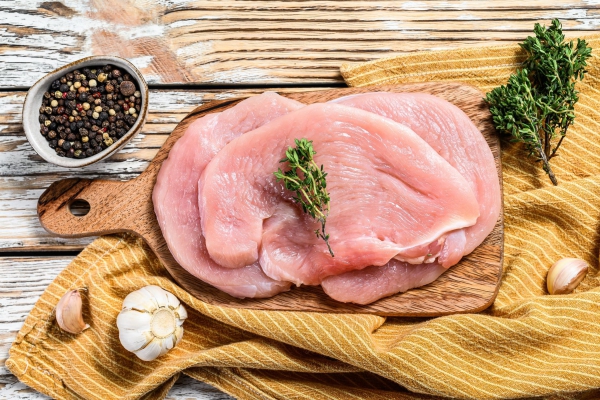 Fresh Turkey steaks with thyme and pepper on cutting board. Raw organic poultry meat. white background. Top view